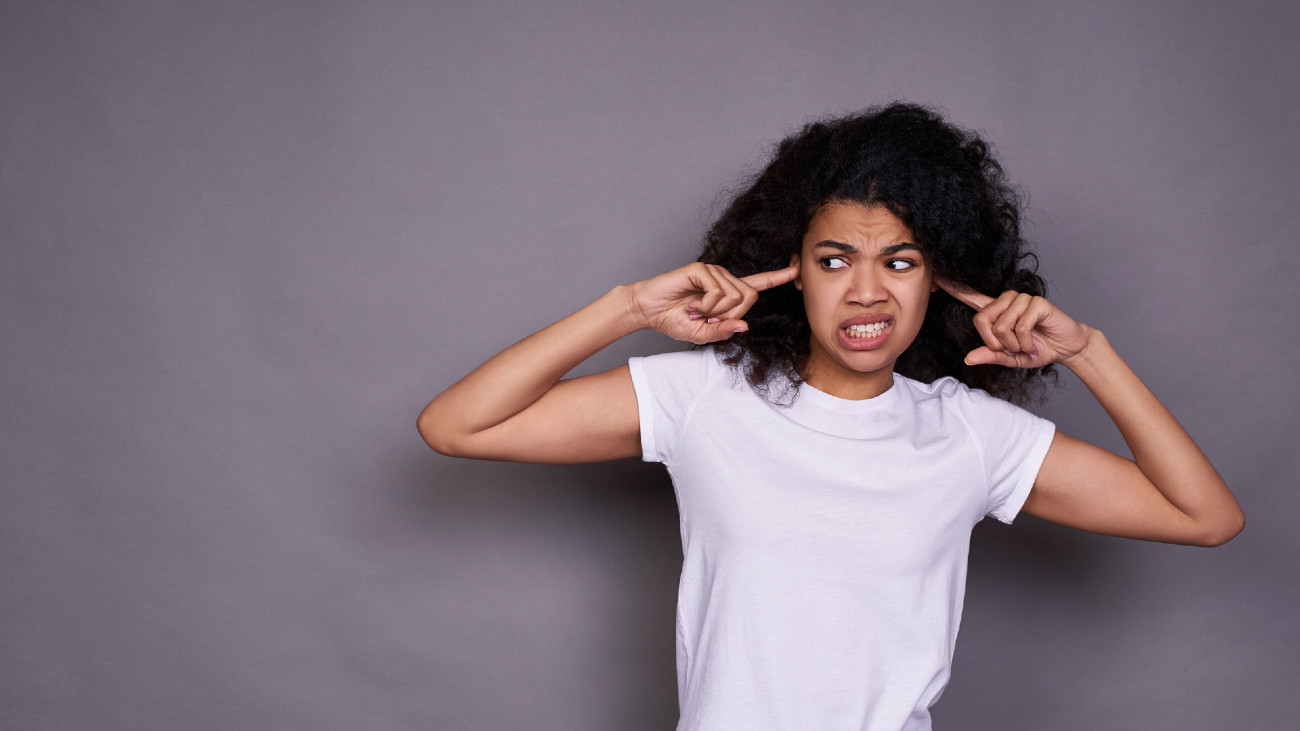 Vrouw met vingers in oren vanwege irritante geluiden