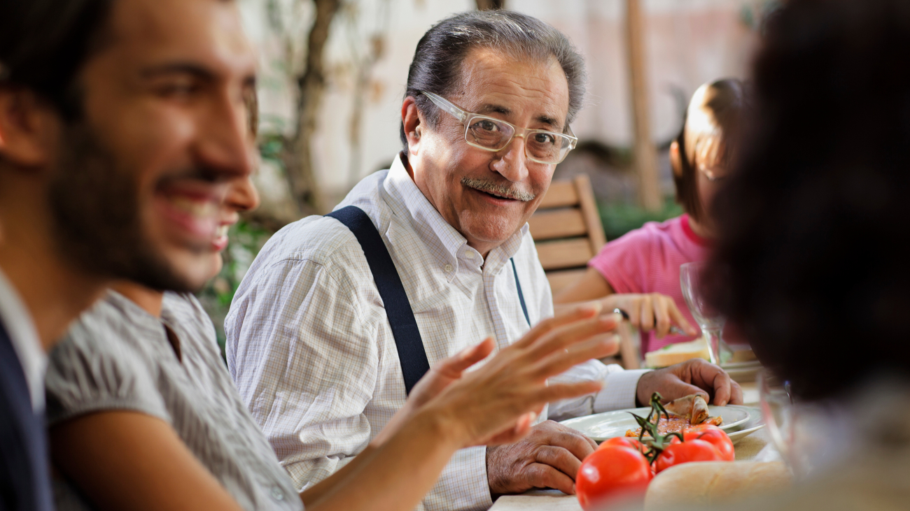 Oude man praat Italiaans met familie aan een grote tafel