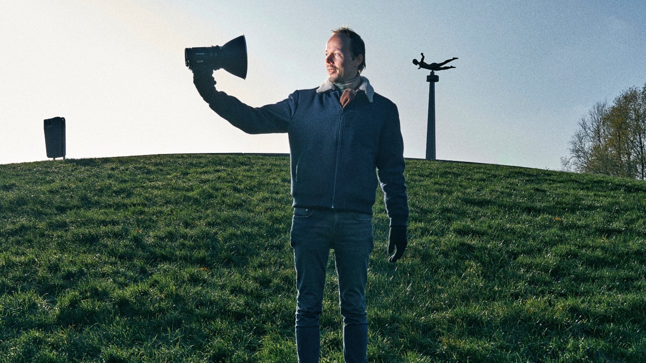 Ivo Nieuwenhuis op een groene heuvel. Hij bestudeert humor in Nederland.