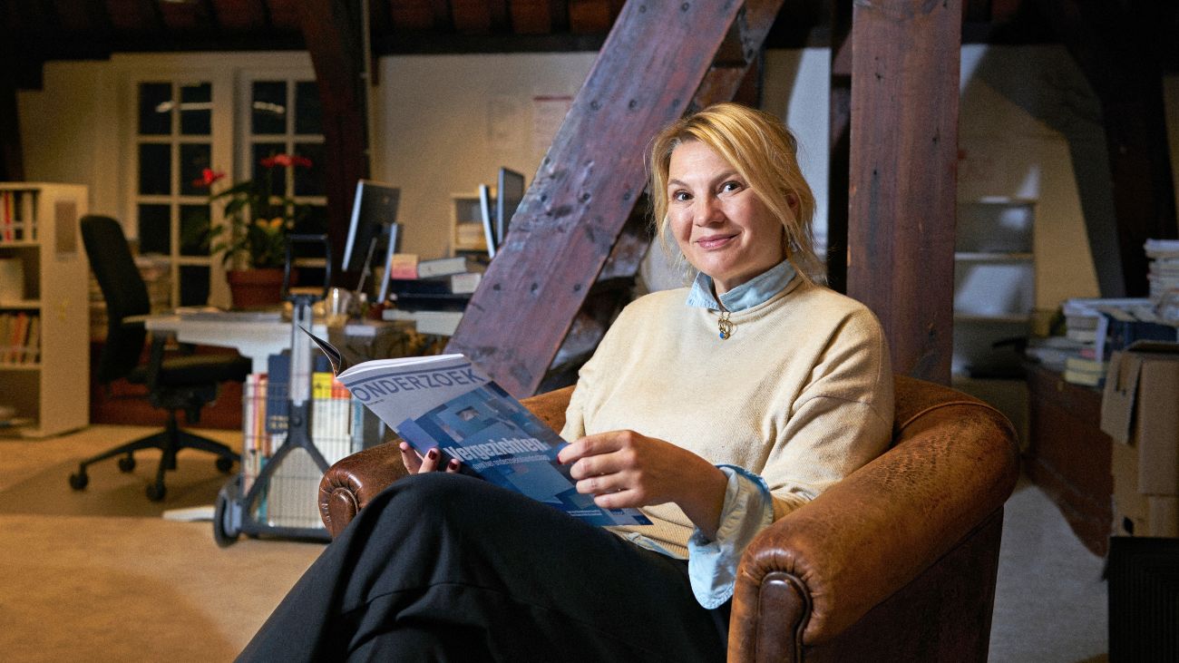 Eveline Crone zit in een stoel een leest een onderzoek over pubers