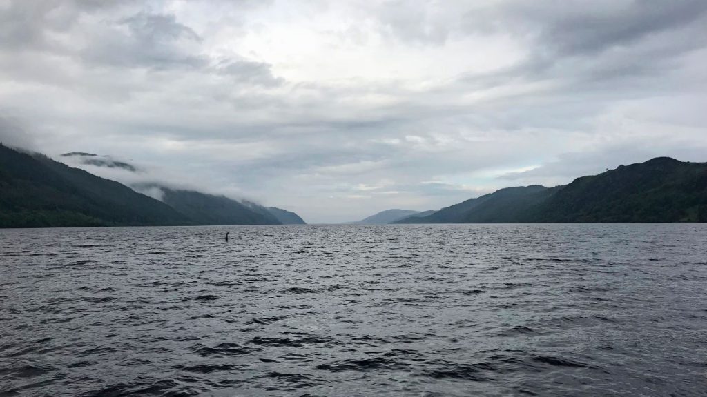 Foto van Loch Ness met in de verte iets wat lijkt op het monster